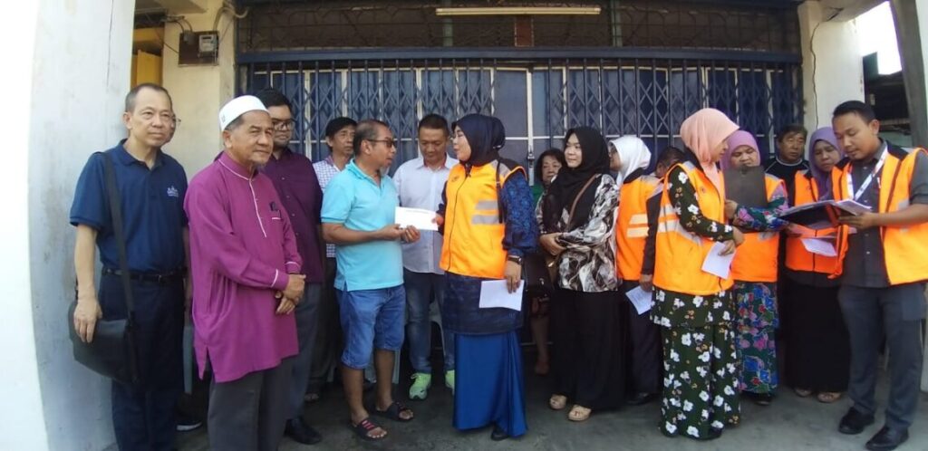 Halimaton (di tengah) menyerahkan bantuan kepada korban kebakaran rumah toko di Pekan Kota Kuala Muda, dekat Sungai Petani hari ini.